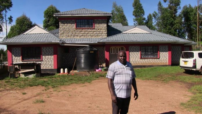 Mr Francis Tonui outside his eight-bedroom dream house that he built using interlocking blocks